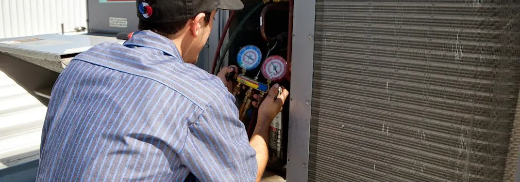 HVAC technician servicing a condenser unit in Gardere